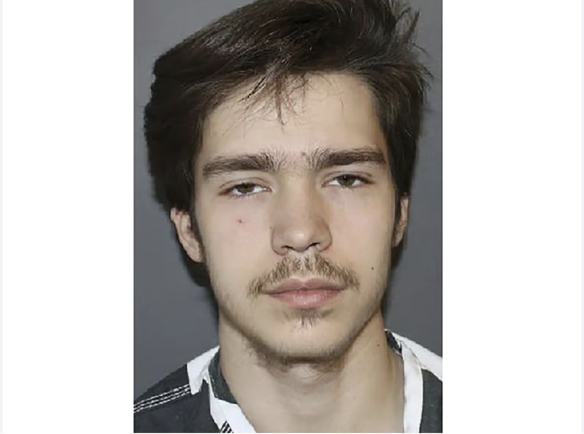 A young man with dark hair and a beard looking directly at the camera.