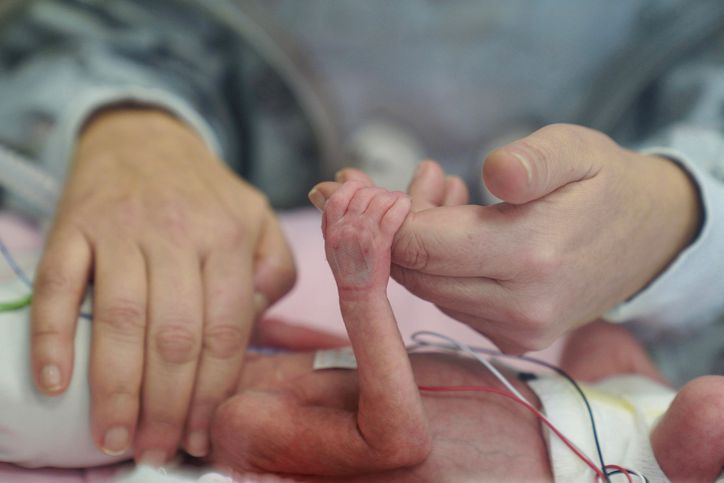 Premature baby holding parent's hand in NICU incubator, symbolizing love, care, support, medical technology, neonatal intensive care, hope, bonding, fragile life, healthcare and parenthood connection.