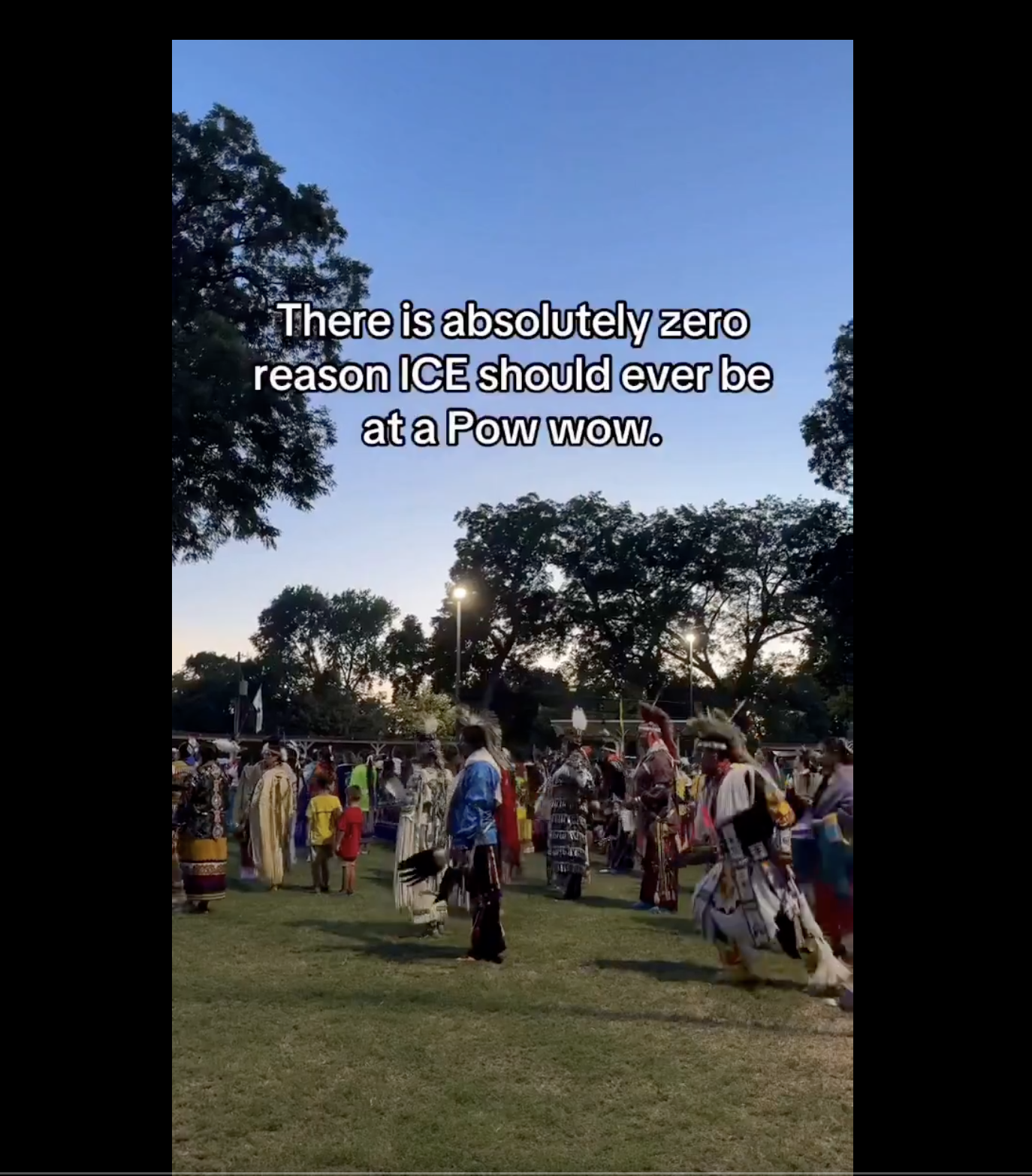A group of people in traditional Native American regalia performing a ceremonial dance in a park setting, with the text "There is absolutely zero reason ICE should ever be at a Pow wow.